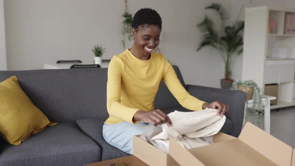 Happy Young African Woman Opening Parcel Box at Home