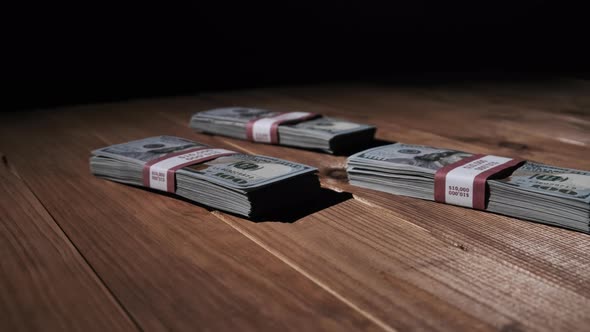 Three Stacks of 10000 American Dollars Banknotes in Bundles Lie on Wooden Table