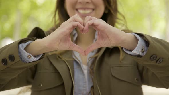 Smiling Woman Making Heart Shape with Hands