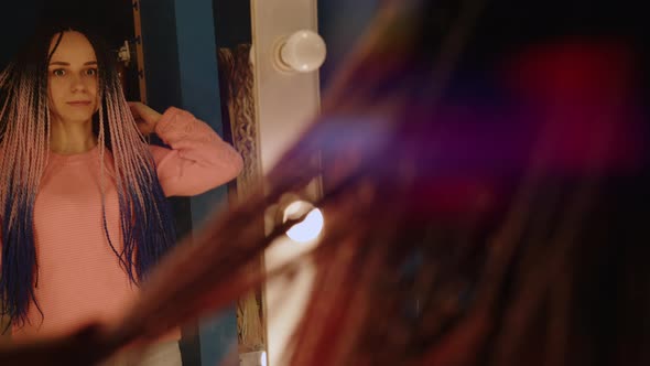 Smiling Young Woman with Dreadlocks Looking at Mirror