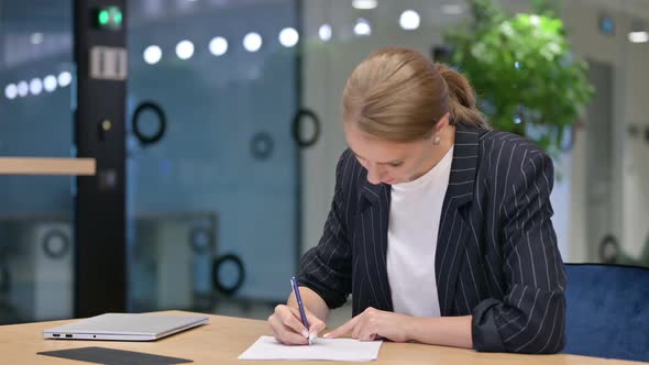 Upset Young Businesswoman Trying to Write on Paper in Office