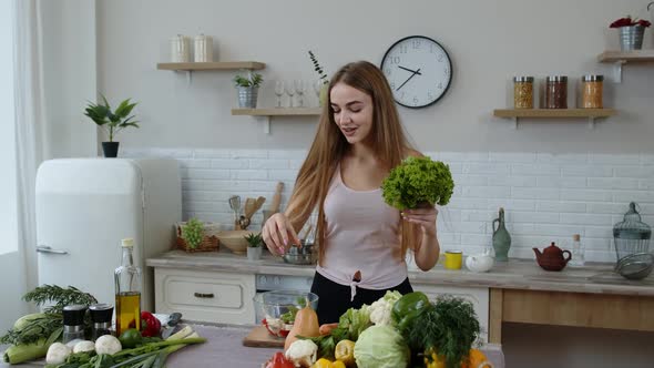 Young Girl Dancing, Having Fun and Cooking Salad with Raw Vegetables. Throwing Pieces of Lettuce
