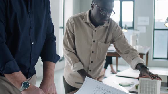 Senior and Young Multiethnic Architects Discussing Floor Plan