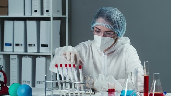 Doctor Wearing Protective Mask Gown and Gloves Taking PCR Tests and Writing Results in Notes