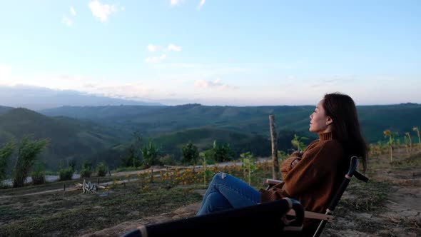 Slow motion of a female traveler sitting and watching sunrise on mountain peak in the morning