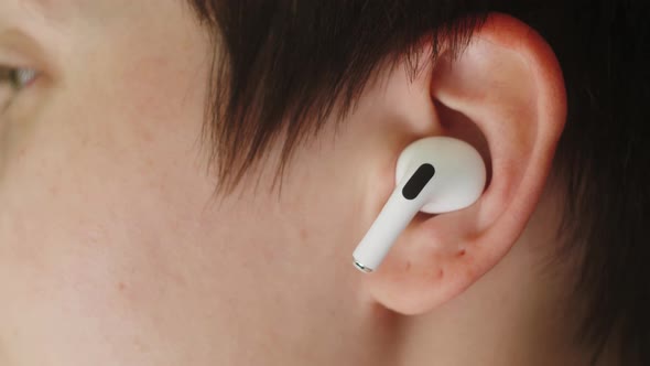 Portrait of a Beautiful Young, with Headphones Wireless in Her Ear, Listens To Music Close Up Macro