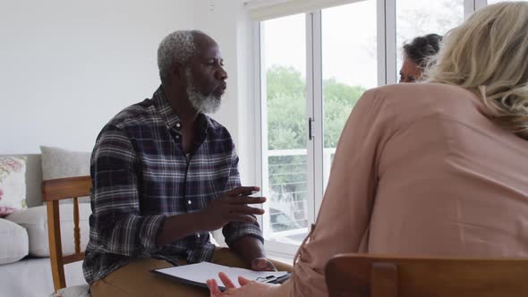 Two diverse senior couples sitting in circle having a therapy conversation at home