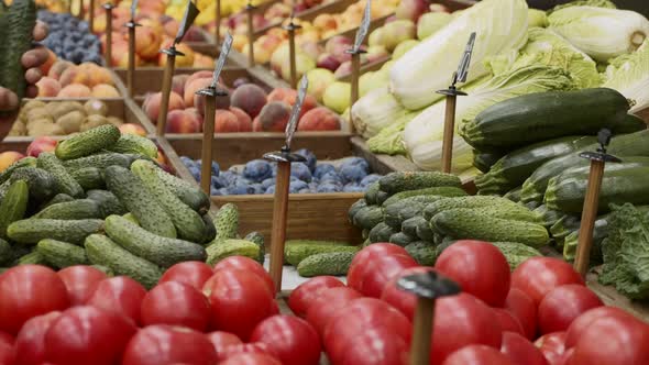 Closeup Hands of Grocery Worker Is Arranging Cucumbers on Store Shelves