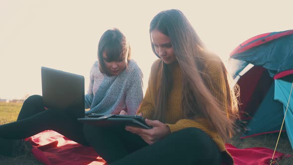 Women with Tablet and Laptop at Comfortable Campsite