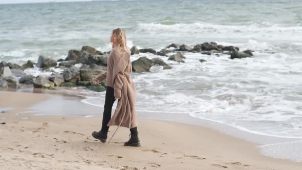 Portrait of Blonde Woman Walking on the Beach in Autumn Sunny Day