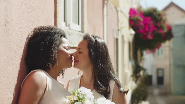 Smiling Lesbian Brides Kissing and Looking at Camera