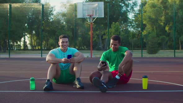 Athletes with Phones Resting on Basketball Court