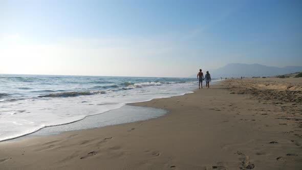 Couple of Lovers Walking at Seashore Holding Hands During Resting on Resort. Man and Woman Strolling