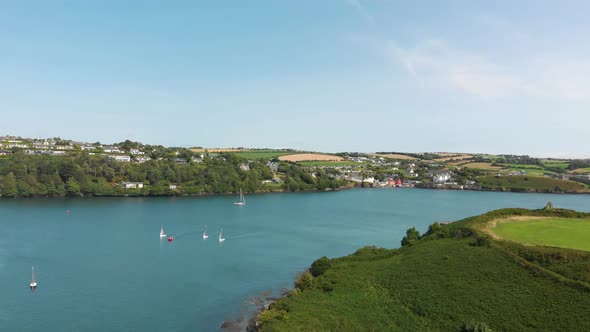 Gorgeous blue green waters form the entrance to this idyllic harbor scene as sailing boats enter and