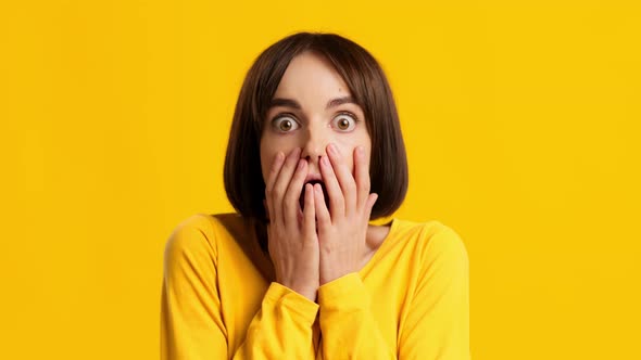 Woman Looking At Camera In Shock Covering Mouth Yellow Background