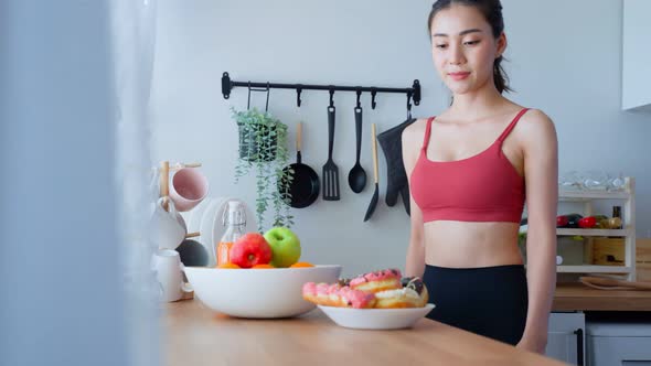 Sport girl in sportswear desire to chose fruit and ignore sweet donut enjoy eat healthy food.