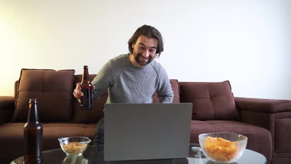 Young Attractive Caucasian Man Celebrating Birthday Online with Bottle of Beer