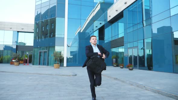 Young Businessman with Briefcase Runs and Looks at His Watch