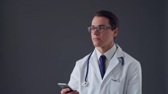 Studio portrait of young professional medical doctor standing over grey background