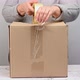 woman in a gray sweater holds a roll of duct tape and packs brown cardboard boxes - VideoHive Item for Sale