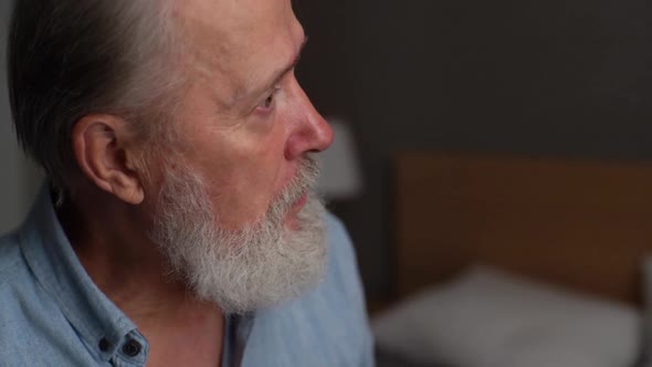 Closeup Face of Serious Grayhaired Handsome Mature Adult Male Talking with Somebody at Home