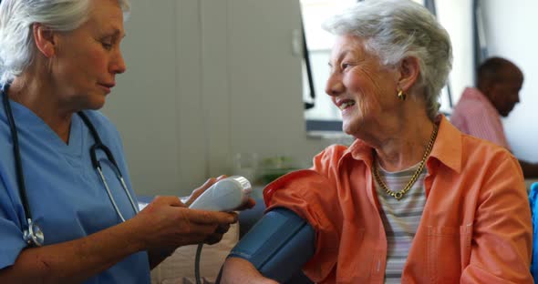 Female doctor checking blood pressure of senior woman 4k