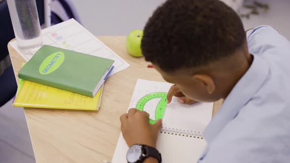 Hardworking Boy Drawing in Geometry Lesson with Protractor Ruler and Pencil