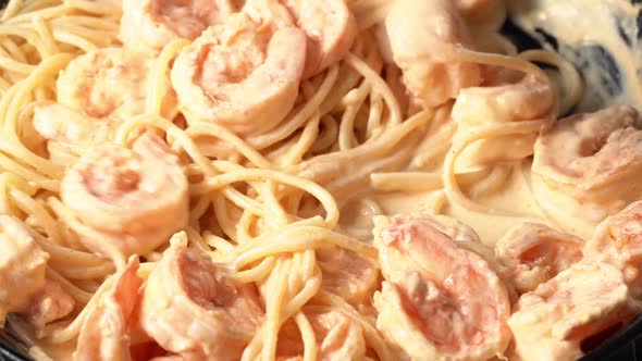 Person Mixing Pasta with Shrimp and Cream Sauce in Frying Pan Spaghetti with Seafood and Rich Cream