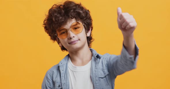 Awesome Curly Boy Showing Like Gesture, Smiling in Sunglasses and Denim Coat