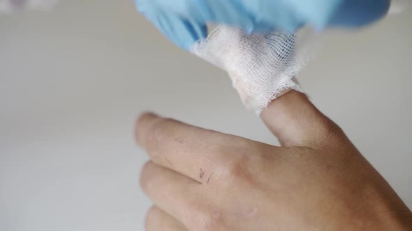 Hands of Doctor in Sterile Gloves Are Going To Be Treated with Antiseptic Wound on the Hand of a Man