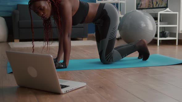 Adult Black Woman Sitting on Yoga Map Watching Online Fitness Workout