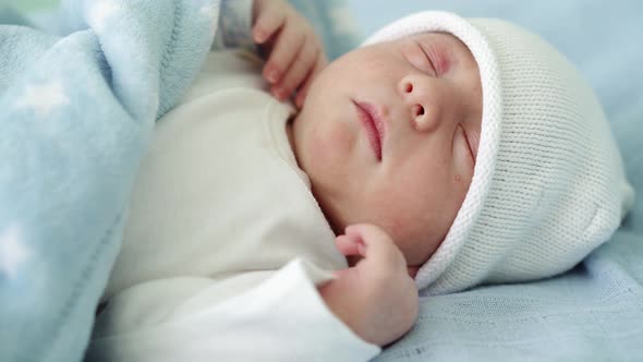 Closeup of Newborn Baby Face Portrait Early Days Sleeping Sweetly On White Blue Background