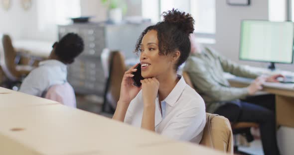 Happy african american businesswoman talking on smartphone in creative office