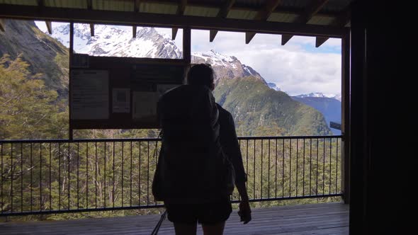 Hiker walking through shelter, viewing snow capped mountain landscape, Routeburn Track New Zealand