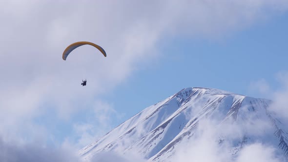 Paraglider flies above the mountain peak