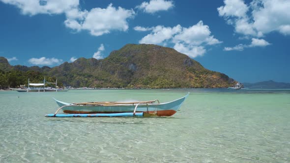 El Nido Bay. Palawan, Philippines. Bangka Boat Floating in Shallow Bay with Village and Mountain in