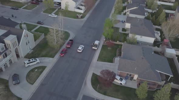drone view of car driving in suburban neighborhood in evening pulling back revealing mountains