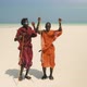 Young Happy Masai Tribe Members in Red Dresses and Sunglasses Dancing on the Sand Beach - VideoHive Item for Sale