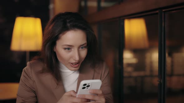 Woman Receiving Shocking Good News on Smartphone at Cafe