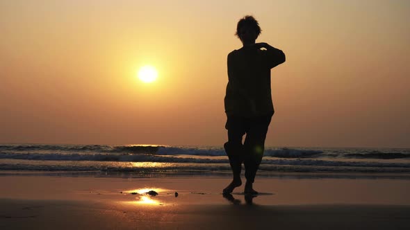 Silhouette of Active Senior Woman Practicing Tai Chi Gymnastic on Sandy Beach.