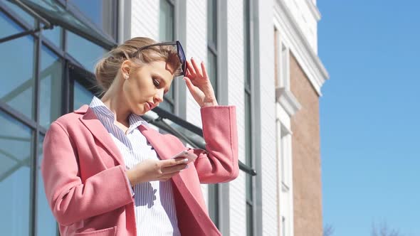 Emotional Girl Talking on the Phone Against the Background of Modern Business Center