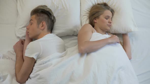 Happy Man and Woman Waking Up in Bed in Morning, Smiling and Holding Hands