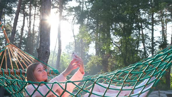 Young Girl Taking Selfie Photo on Cellphone While Lying in Hammock