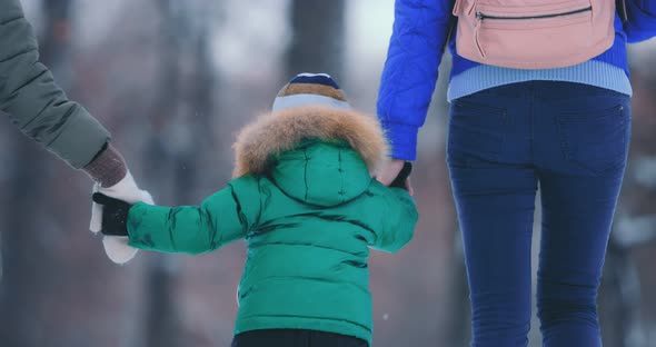 Young Mother Walks with Children They Hold Hands