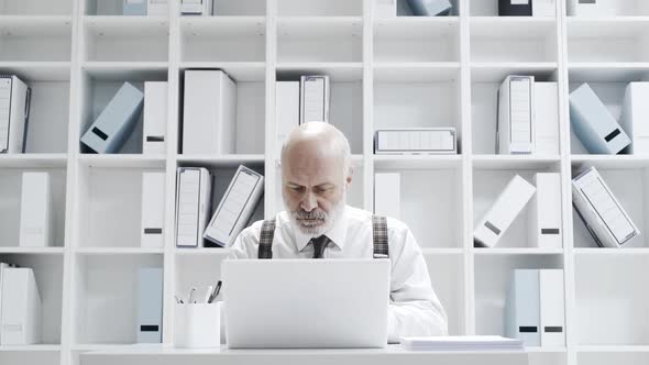 Stressed businessman smashing his laptop with a bat