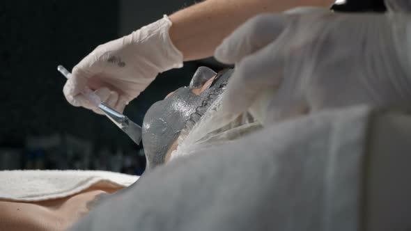 Portrait of Young Woman Laying in Spa Cosmetology Salon with Dark Mask on Her Face. Beauty Facial