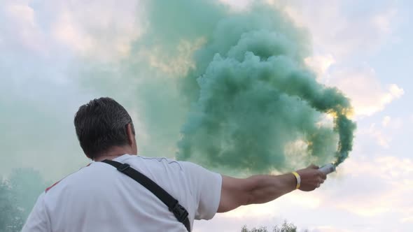 Man Having Fun with Colorful Smoke Flares Against the Sky. Slow Motion