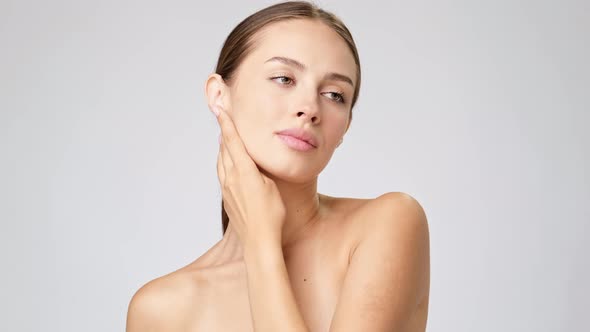 Beautiful Young Woman with Clean Fresh Skin Standing Over Light Grey Background