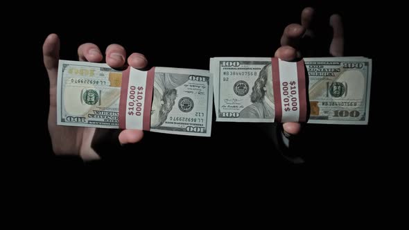 Two Stacks of 10000 American Dollars Bundles in Male Hands on Black Background