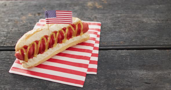 Video of hot dog with mustard and ketchup with flag of usa on a wooden surface